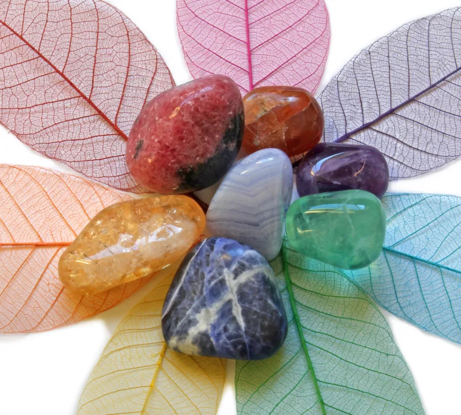 Colourful chakra stones arranged on delicate leaves